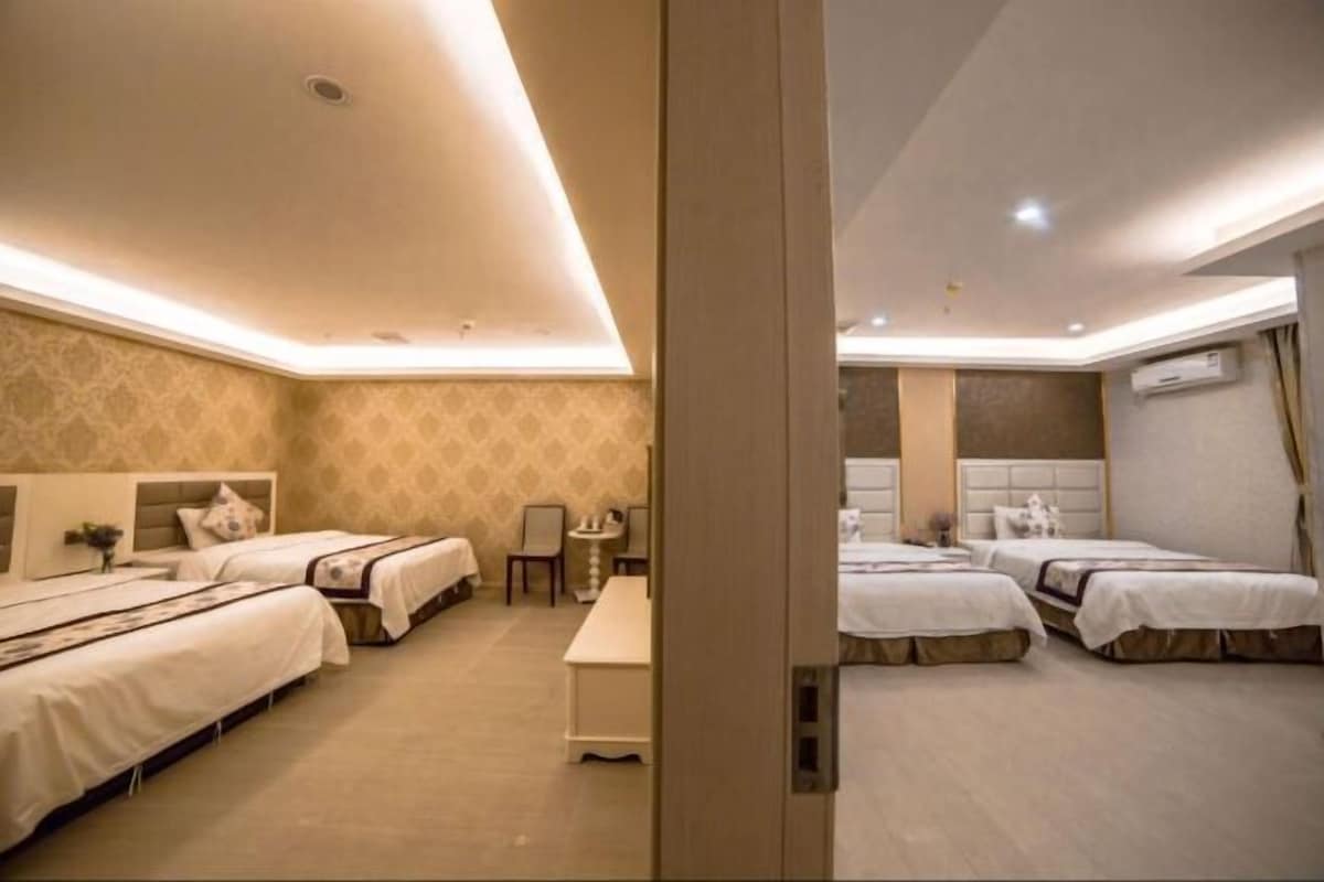A hotel room with three beds, a small table, and a chair.