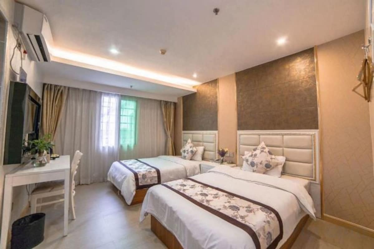 A hotel room with two beds, a desk, and a chair.