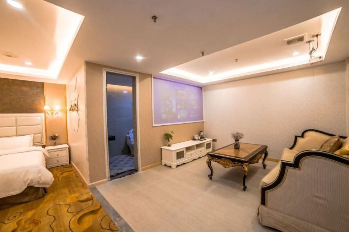 A hotel room with a bed, a sofa, a coffee table, a TV, and a small cabinet.