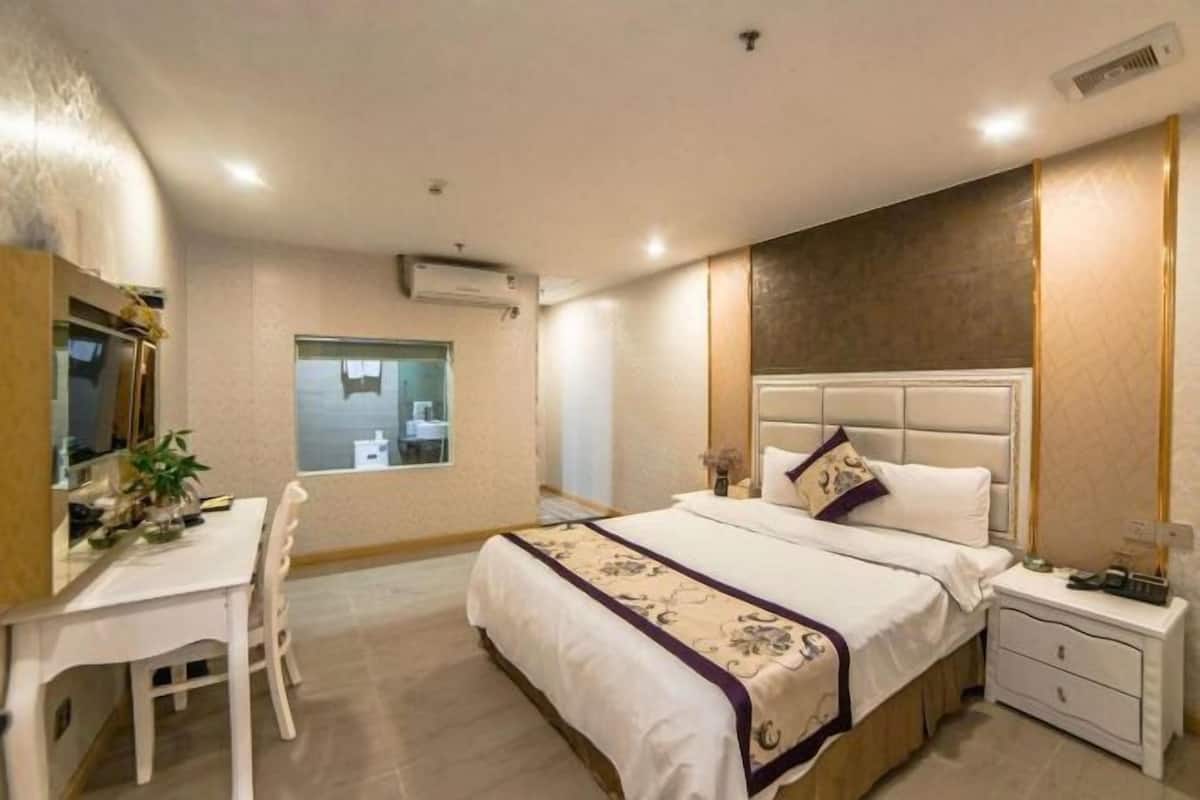 A bedroom with a bed, bedside table, nightstand, desk, chair, and a window.