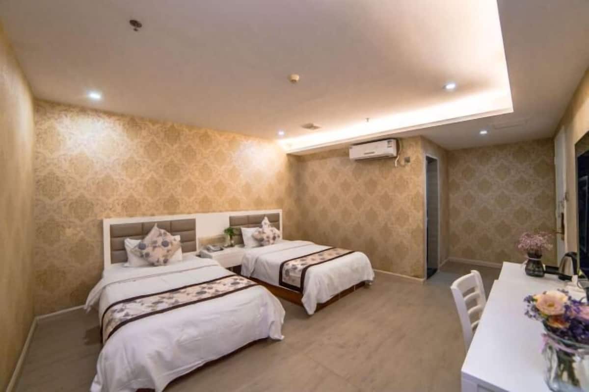 A hotel room with two beds, a dining table, and a small kitchen area.