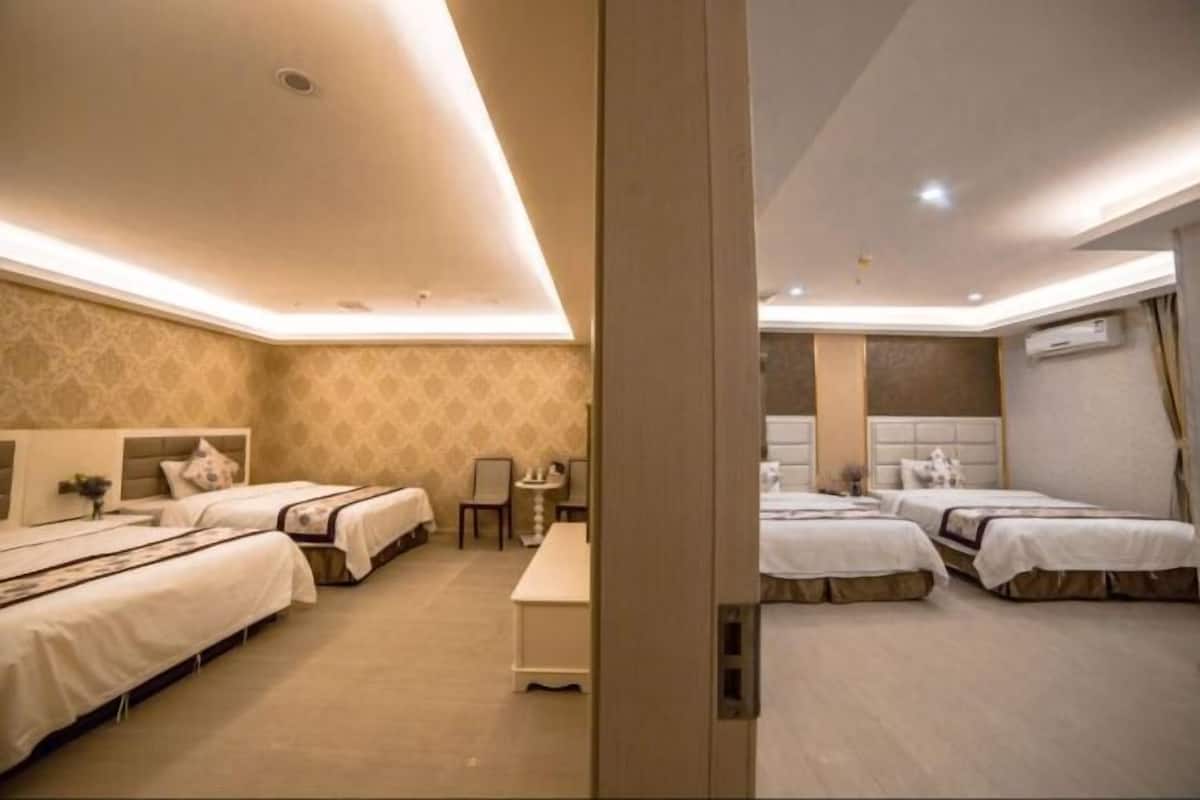 A hotel room with three beds, a small table, and a chair.