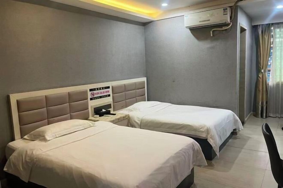 A hotel room with two beds, a desk, and a chair.