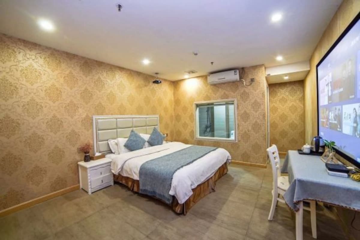 A bedroom with a bed, bedside table, chair, and a desk with a computer.