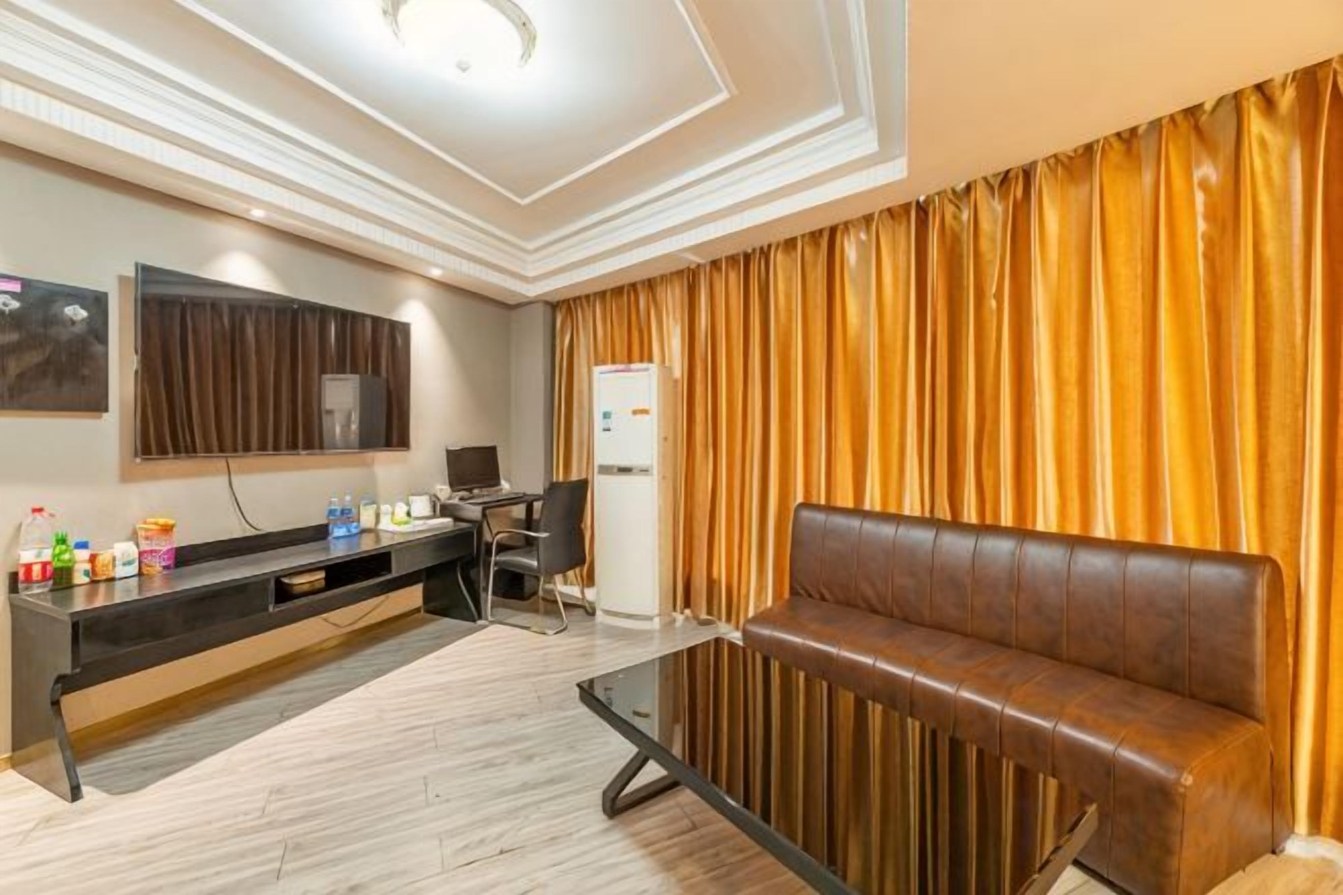 A hotel room with a sofa, a flat-screen TV, a desk, and a minibar.