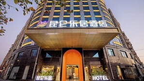 Een hotel met een modern design, met een opvallende entree met een oranje boog en een groot verlicht bord.