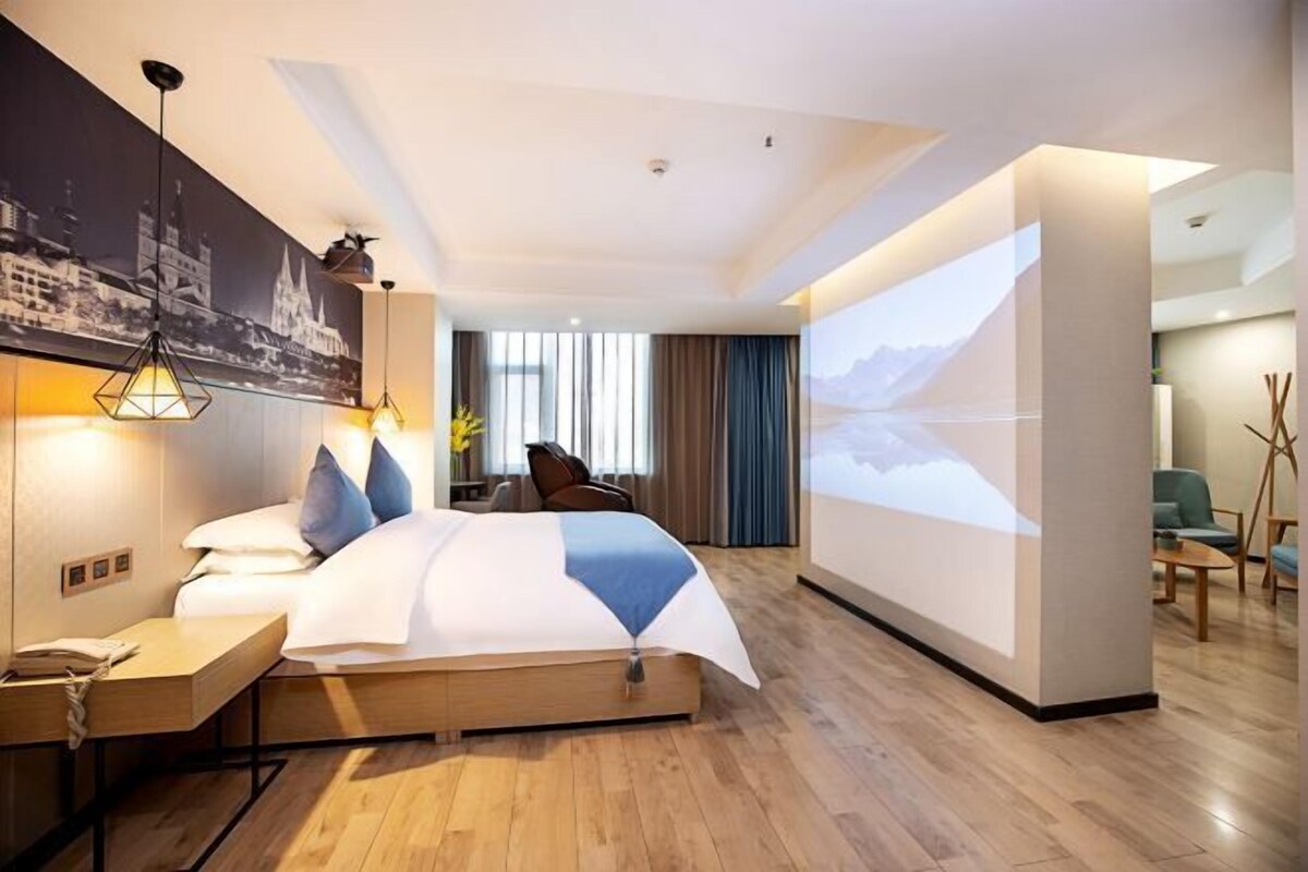 Ein modernes Hotelzimmer mit einem großen Bett, einem Schreibtisch, einem an der Wand montierten Fernseher und einem Stadtbild.