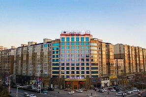 A multi-story hotel with a central entrance, multiple floors, and a parking area in front. - Kunlun Leju Hotel (Wenxian Branch) (Wen County)
