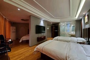 A hotel room with two beds, a flat-screen TV, a desk, and a mirror.