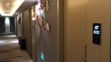 A hotel corridor with a wooden door marked '8202' and a digital sign.
