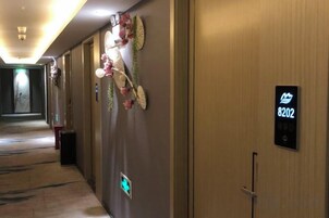 Un pasillo de hotel con una puerta de madera marcada '8202' y un letrero digital.