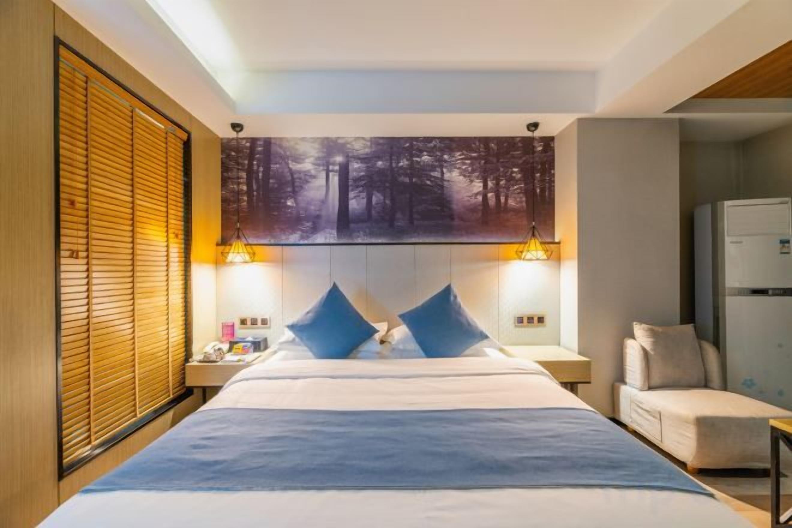 A hotel room with a large bed, two bedside tables, a chair, and a painting on the wall.