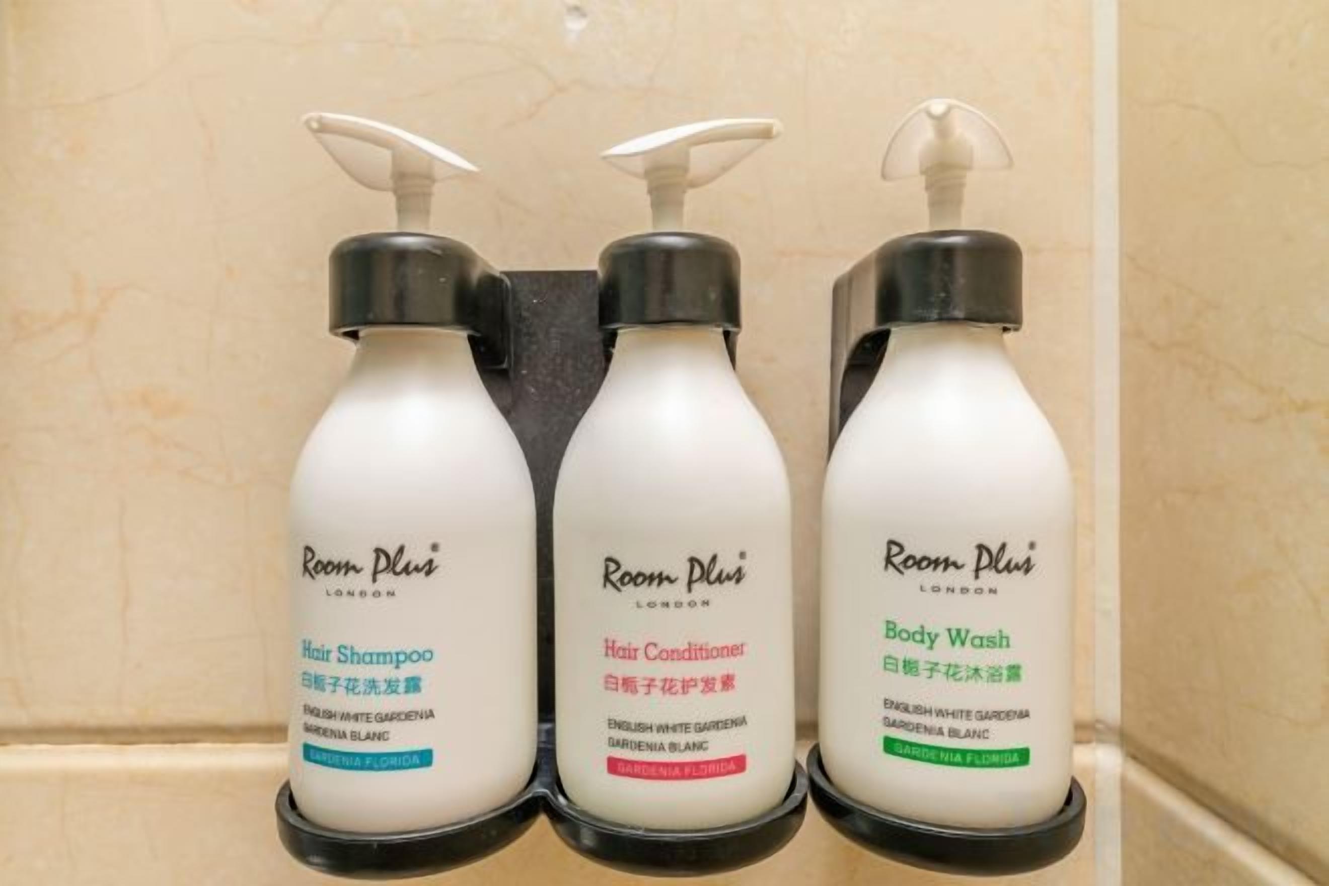 Three bottles of Room Plus products: hair shampoo, hair conditioner, and body wash.