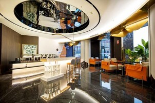 A modern hotel lobby with a central reception desk, seating area, and a large circular skylight.