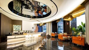 Een moderne lobby met een centraal receptiebalie, een zithoek en een groot reflecterend plafond.