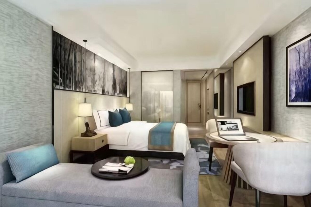 Une chambre d’hôtel moderne équipée d’un lit, d’un bureau, d’un canapé et d’une télévision.