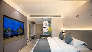 Een moderne hotelkamer met een groot bed, een flatscreen televisie, een kunstwerk aan de muur en een nachtkastje.