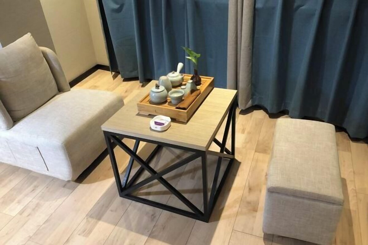 Ein Zimmer mit einem Holztisch, zwei beigefarbenen Sofas und einem Holztablett mit Teekannen und Tassen.