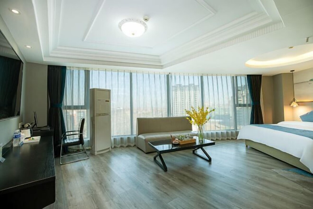 Ein Hotelzimmer mit Bett, Sofa, Couchtisch, Schreibtisch und Fernseher.