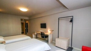 A hotel room with two beds, a desk with a chair, a small cabinet, a red chair, and a round table. - Jinjiang Inn Fuyang Yingshang Road (Fuyang)
