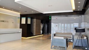 A hotel reception area with a reception desk, seating area, and a glass partition. - Jinjiang Inn Fuyang Yingshang Road (Fuyang)