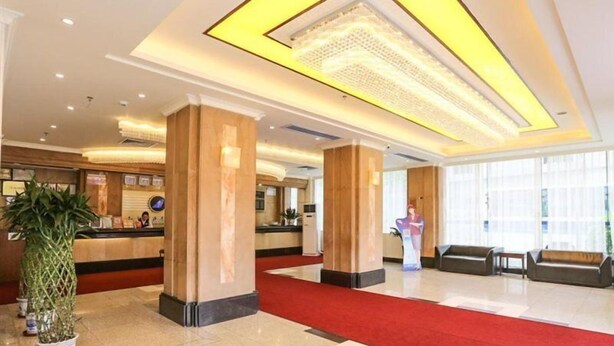 A hotel lobby with a reception desk, large pillars, a red carpet, and a large window providing natural light. - Guangzhou Southern Airlines Pearl Business Hotel (Guangzhou)
