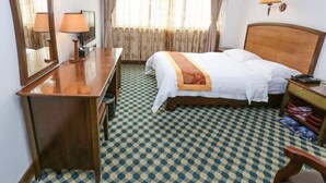 A hotel room with a wooden bed, a desk with a lamp, a mirror, and a window with curtains. - Guangzhou Southern Airlines Pearl Business Hotel (Guangzhou)
