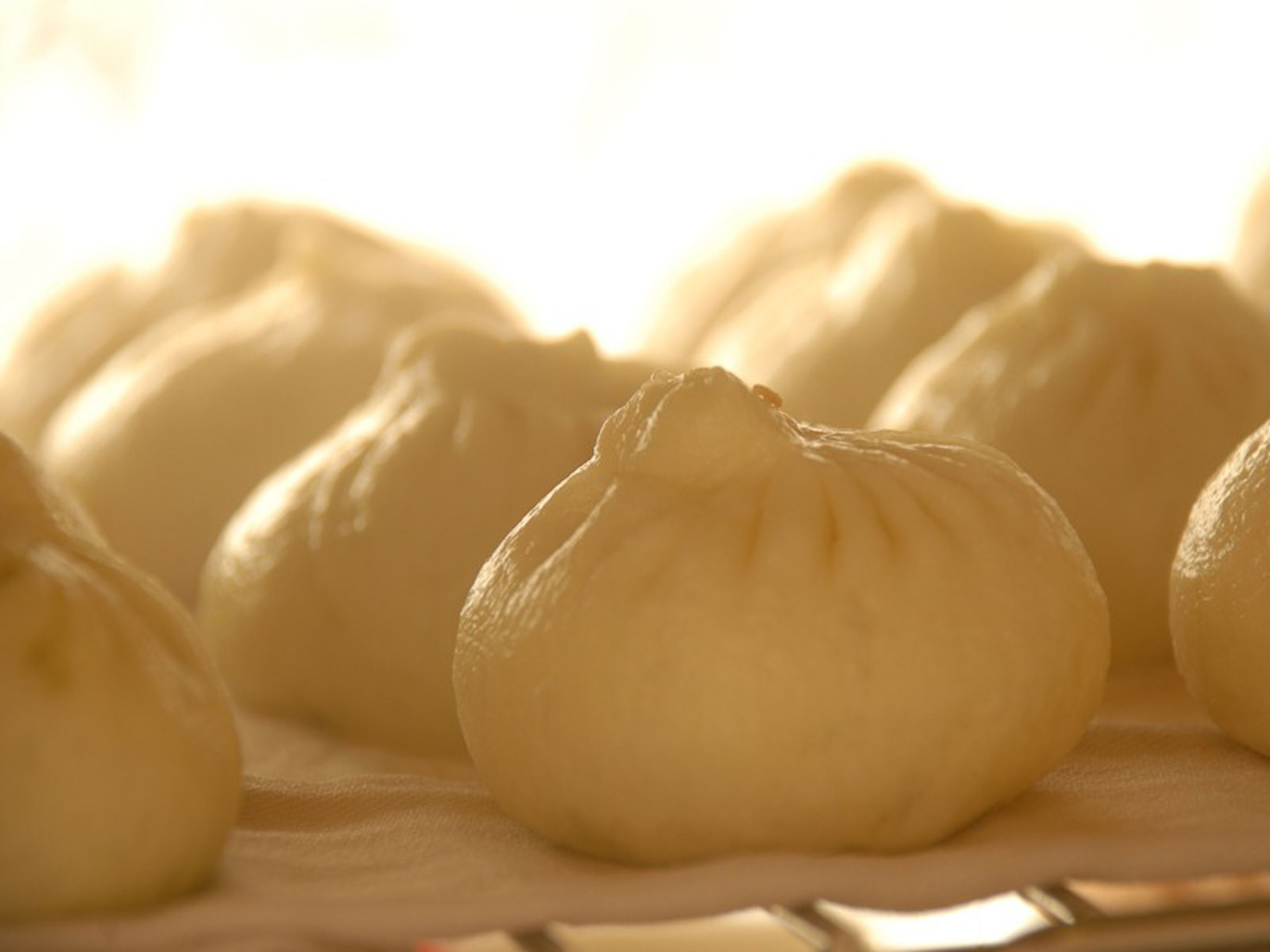 A close-up of several steamed buns on a tray.