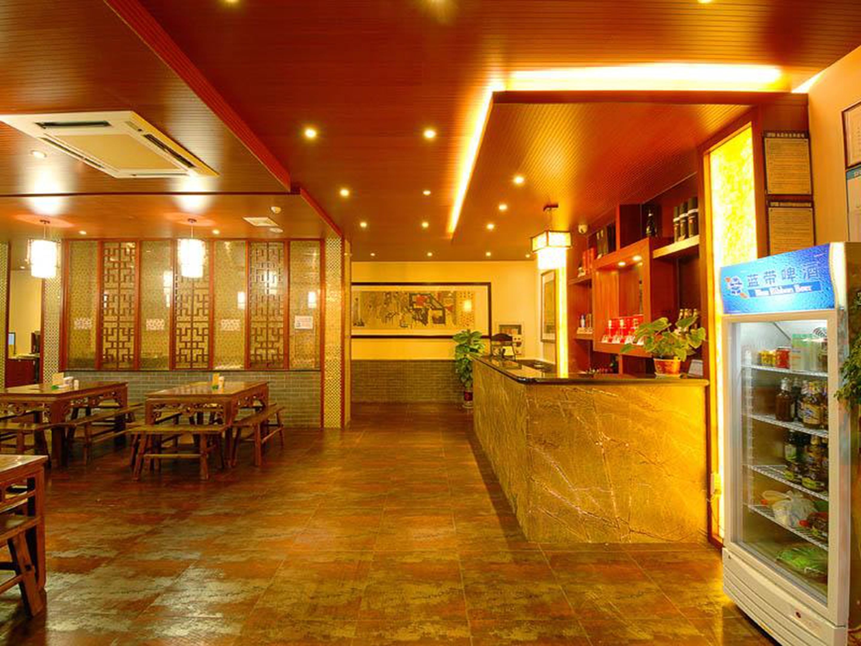 A restaurant with wooden furniture, a counter, and a refrigerated display.