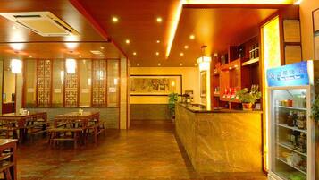 A restaurant with wooden furniture, a counter, and a refrigerated display.