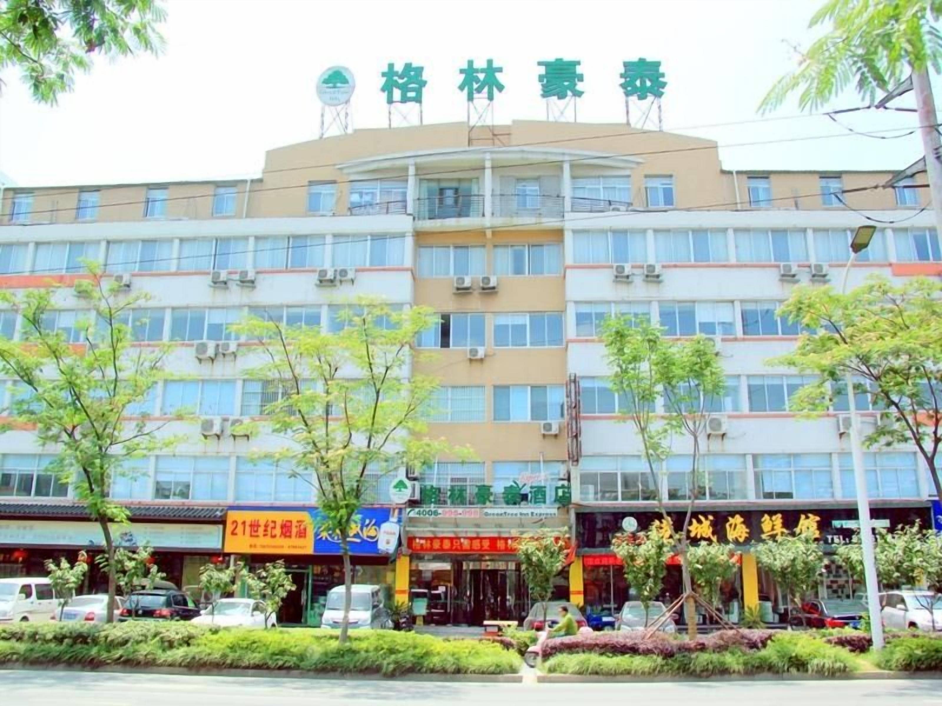 A multi-story building with a sign indicating a hotel. There are several storefronts with visible signage below the hotel.