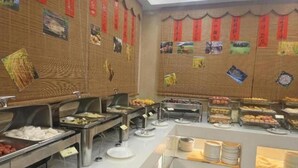 A buffet setup with various food items and a wall decorated with red banners and pictures. - Vienna Hotel Chaoyang Road - Nanning (Nanning)