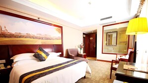 Une chambre d’hôtel avec un grand lit, un bureau, une chaise, une lampe de bureau et un grand miroir.