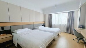 Une chambre d’hôtel avec deux lits, un bureau et une chaise.