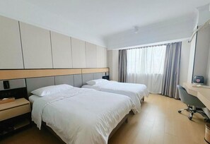 Une chambre d’hôtel avec deux lits, un bureau et une chaise.