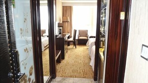 Een hotelkamer met een bed, een bureau, een stoel, een lamp en uitzicht.