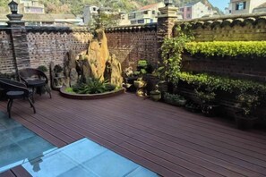 A wooden deck with a brick wall, potted plants, and a stone feature. - Yandang Huating Villa (Wenzhou)
