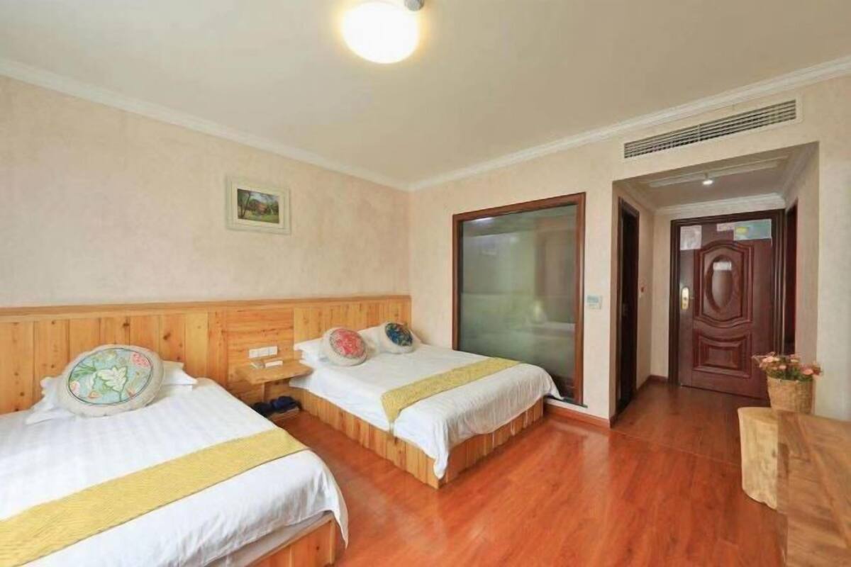 Ein Hotelzimmer mit zwei Betten, Holz-Kopfteilen, einem großen Fenster und Holzboden.