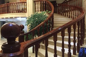 Een statige trap met een houten leuning en balustrades, die naar een verdieping leidt.