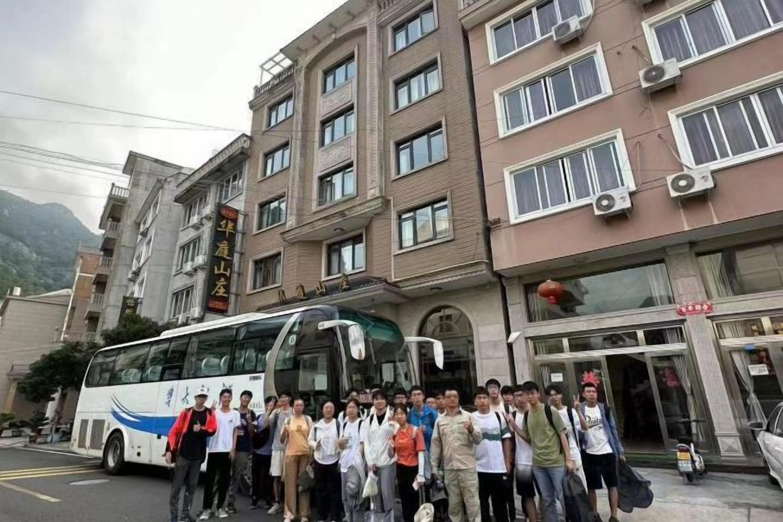 A group of people standing in front of a building with a bus parked nearby.