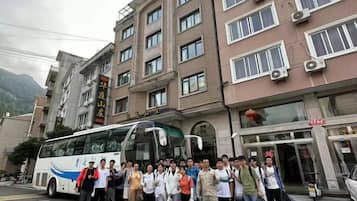 A group of people standing in front of a building with a bus parked nearby.
