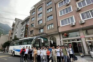 A group of people standing in front of a building with a bus parked nearby. - Yandang Huating Villa (Wenzhou)