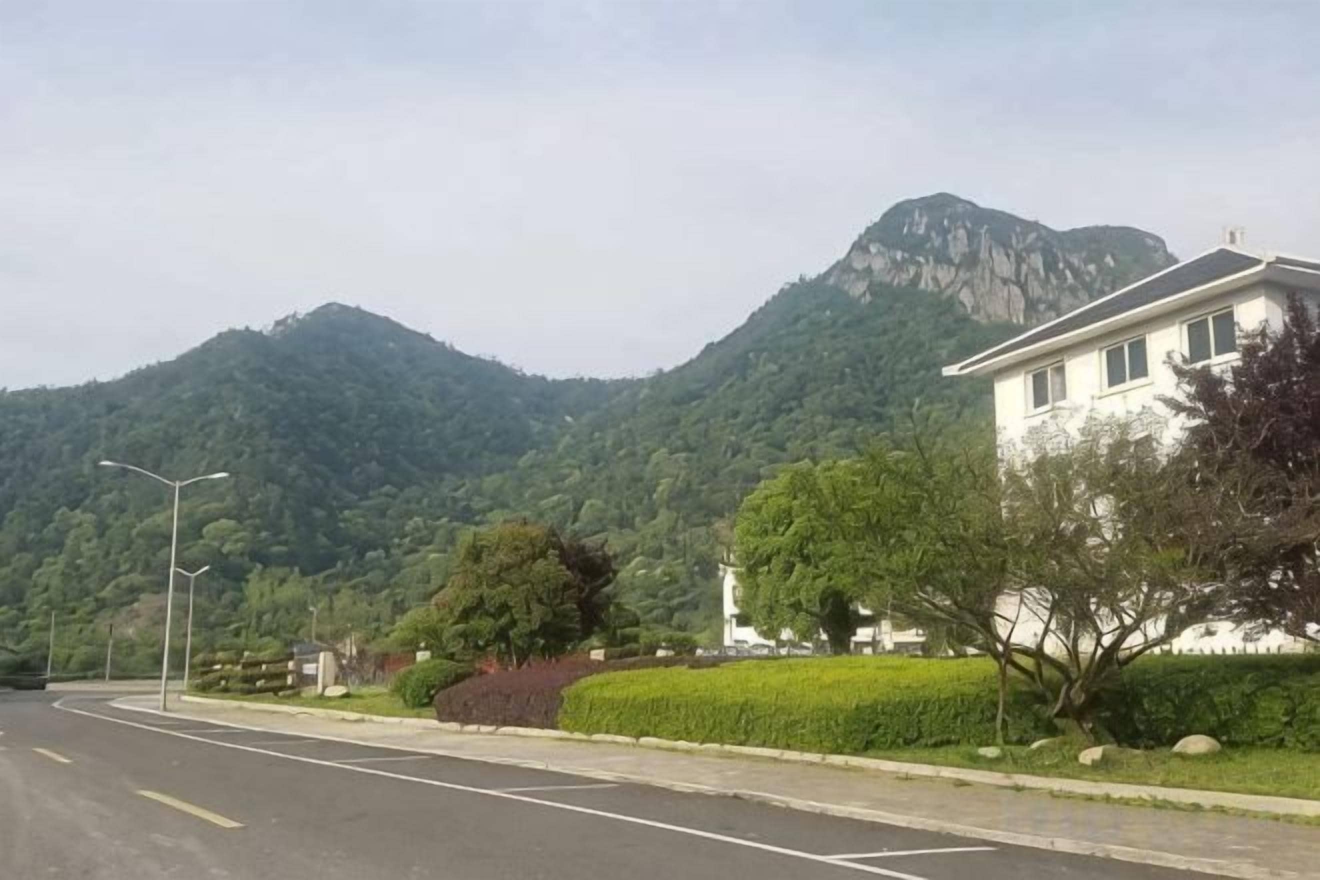 A residential street with a house, a mountain, and a clear sky.