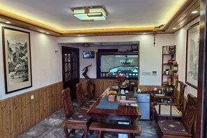 A dining area with a long wooden table, chairs, a television, and a bookshelf. - Yandang Huating Villa (Wenzhou)