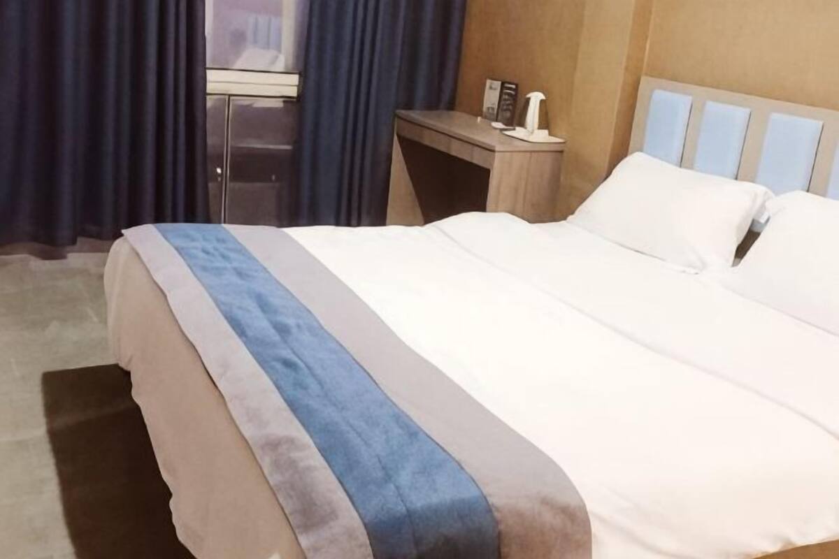A hotel room with a bed, a desk, a chair, and a window with curtains.