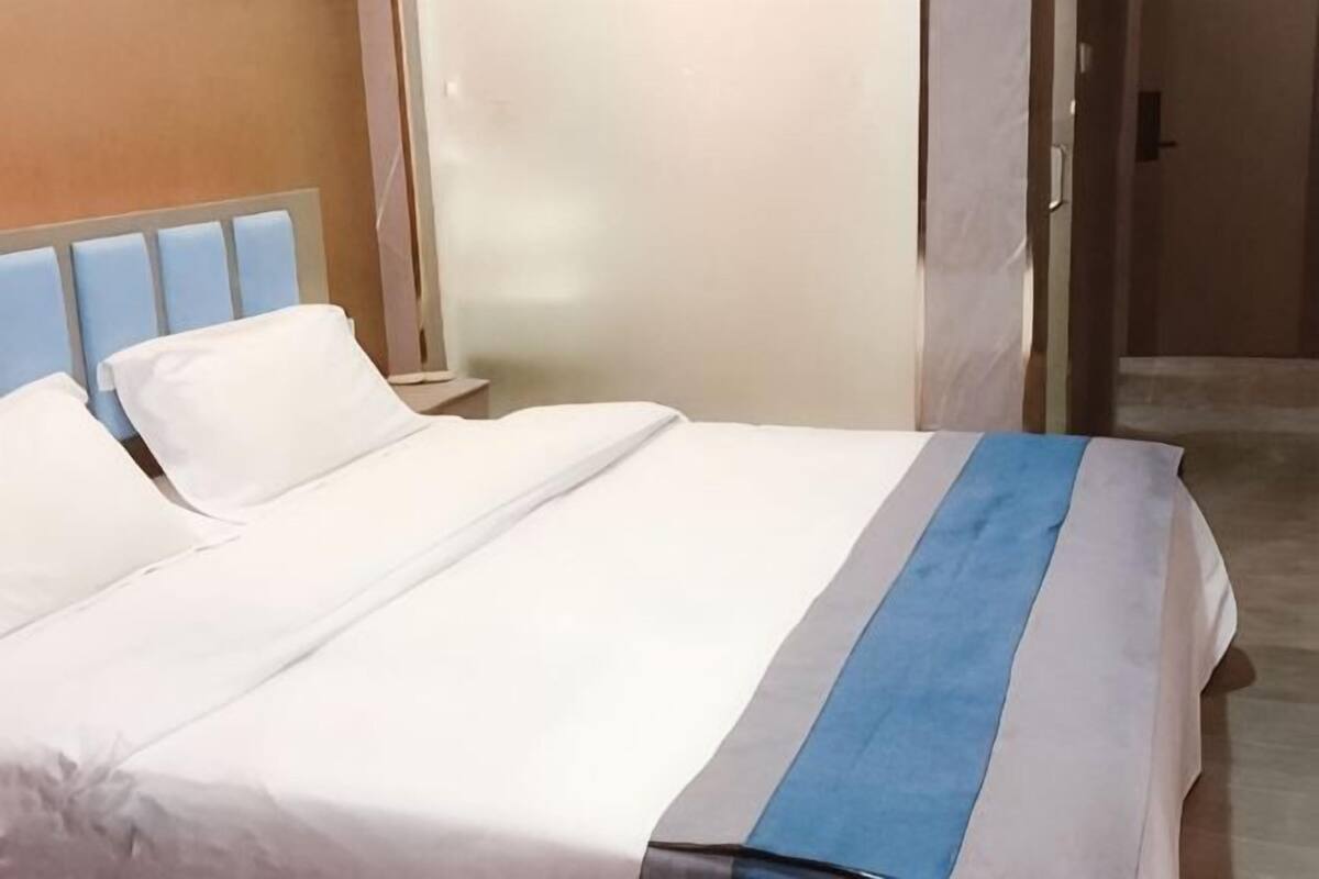 A hotel room with a bed, a nightstand, and a door.