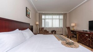 A hotel room with a large bed, a desk, a chair, a television, and a window with curtains. - Yellow River Pearl Hotel (Yinchuan)