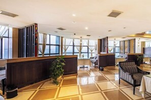 A hotel lobby with a reception desk, seating area, and large windows. - Jiaqi Landscape Hotel (Chizhou)
