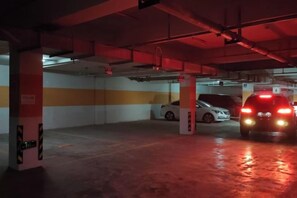 A parking garage with a white car and a red car. - Jiaqi Landscape Hotel (Chizhou)