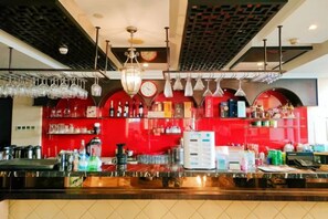 A bar area with a red wall, hanging lights, and various bar equipment. - Jiaqi Landscape Hotel (Chizhou)